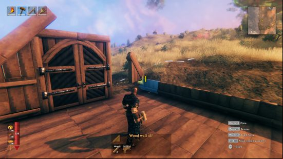 Best building games: A player builds a wooden structure in a meadow in Valheim