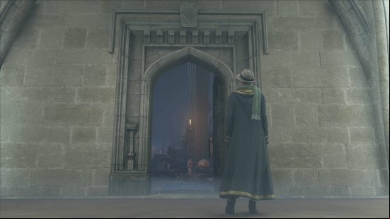 Hogwarts Legacy Room of Requirement - the door to the Room of Requirement appears on a blank wall near the player character, who is dressed in Hufflepuff robes, a scarf, and a trilby hat.