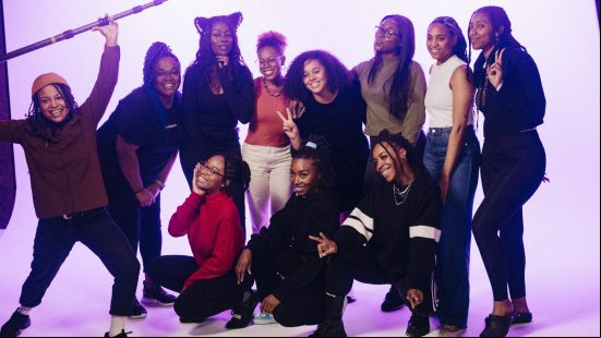 A group of black women stand in a photoshoot area posing for a picture