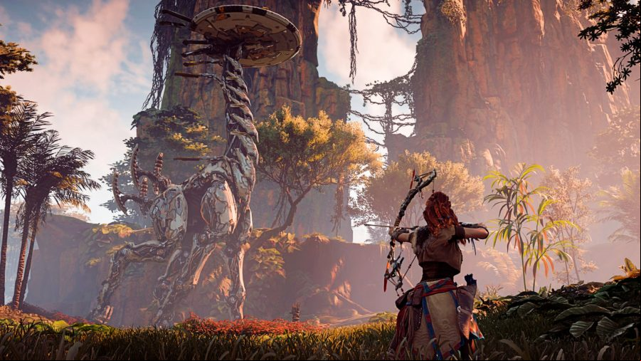 Horizon Zero Dawn - hero Aloy draws her bow as a giant Tallneck robot walks past her through the forest