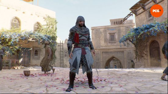 Basim is wearing his Assassin's Creed Valhalla costume over the top of his AC Mirage outfits. He is standing in a street filled with rose petals as a man looks the other way.