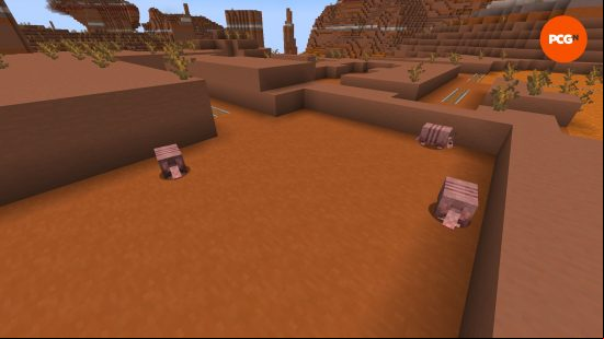 Three Minecraft armadillo appear above a cave entrance in a badlands biome.