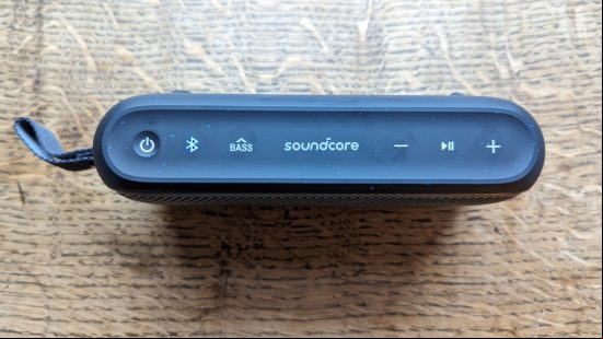 Anker Soundcore Motion 300 review: a black speaker with silver grille appears on a wooden surface.