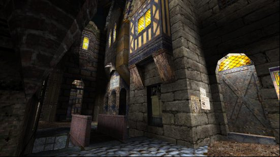 A gloomy city street, with a tall stone building with light coming out of the window. 