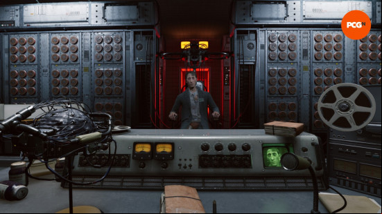 Karma the Dark World review: A man in a suit jacket sits between computer terminals and a desk with a microphone and helmet on it, Sean Mehndez from Karma The Dark World.